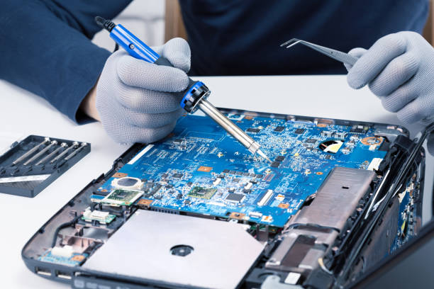 Man engineer soldering a circuit boards in her tech office. Repairman repairing computer component, close-up. stock photo