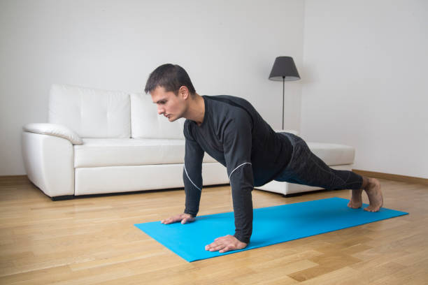 Man exercising at home Young man exercising at home, doing push-ups. About 25 years old Caucasian man. 20 29 years stock pictures, royalty-free photos & images