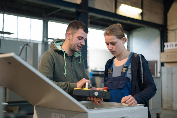 A man explains a control box in a production facility to a trainee stock photo