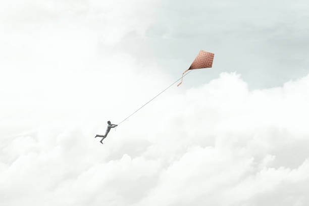 man flying with his red kite in the sky, surreal stock photo