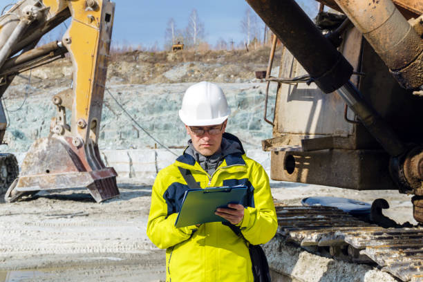 man geologist or mining engineer at work man geologist or a mining engineer writes something in a map-case amid a quarry with construction equipment geologist stock pictures, royalty-free photos & images