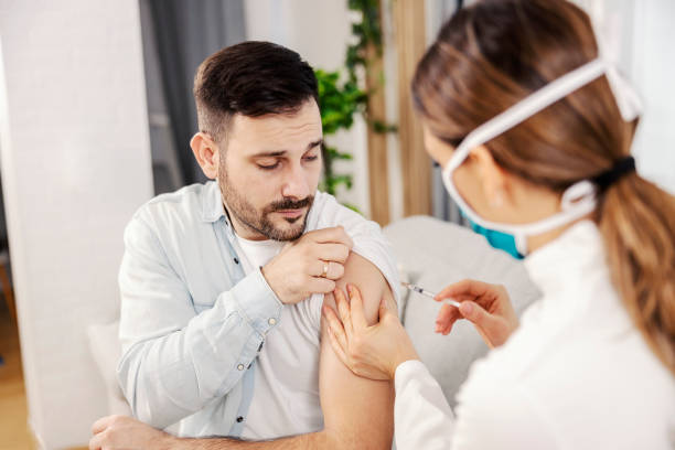 A man getting covid 19 vaccine at his home. stock photo