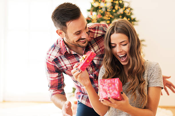 man giving a christmas present to his girlfriend - cadeau geven stockfoto's en -beelden