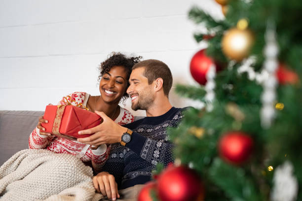 man geeft kerstcadeau aan vrouw - cadeau geven stockfoto's en -beelden