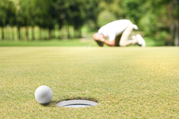 Man golfer feeling disappointed after a putted golf ball missed the hole stock photo