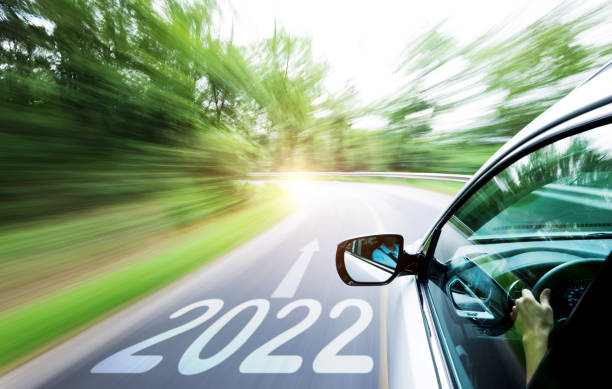 Man hand driving car through the forest, with number 2022 on the road stock photo