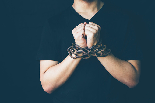 conceptual image of  man hands bondage with rusty old metal chain  over black in the dark room background, can be used for freedom or liberty  concept or christian concept of spiritual bondage