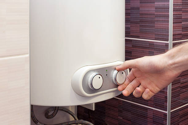 man hands setting the temperature of water in electric boiler - boiler stockfoto's en -beelden