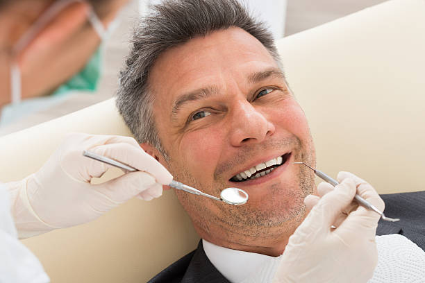 Man Having Dental Check-up In Clinic Happy Mature Man Having Dental Check-up In Clinic dental cavity stock pictures, royalty-free photos & images