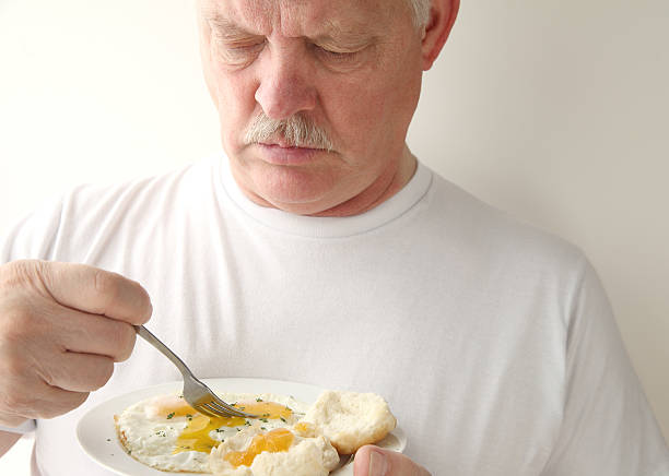 man having fried eggs and biscuits stock photo