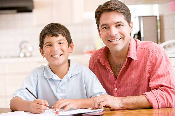 hombre ayudando a young boy in kitchen hacer los deberes - latin family fotografías e imágenes de stock