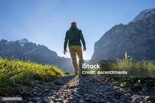 istock Man hikes along grassy mountain ridge at sunrise 1350008705