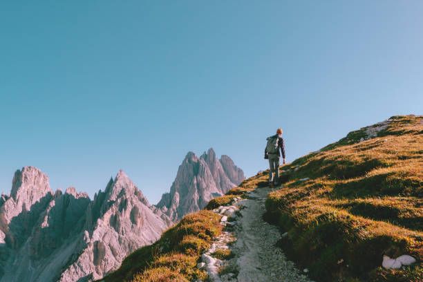 Man hiking alone on the edge of the rock and looking towards the horizon. Italian alps near the Tre Cime di Lavaredo. stock photo