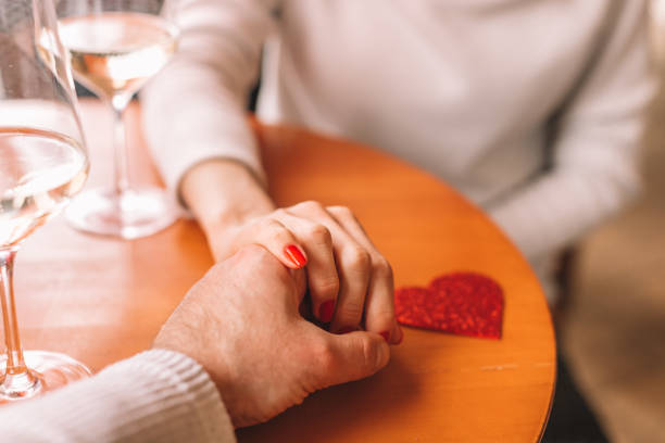 Man holding a hand of his girlfriend while drinking champagne in restaurant stock photo