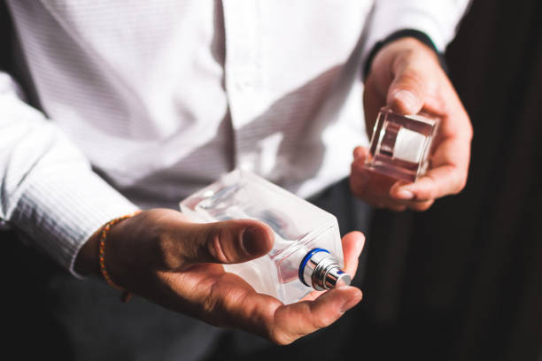 Man holding bottle of perfume and smells fragrance stock photo