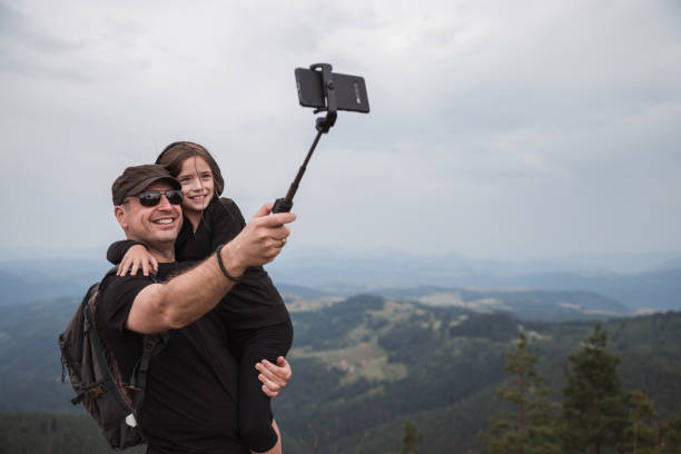 Man holding daughter and taking a selfie Father and daughter taking a selfie via smartphone on a mountain fathers day stock pictures, royalty-free photos & images