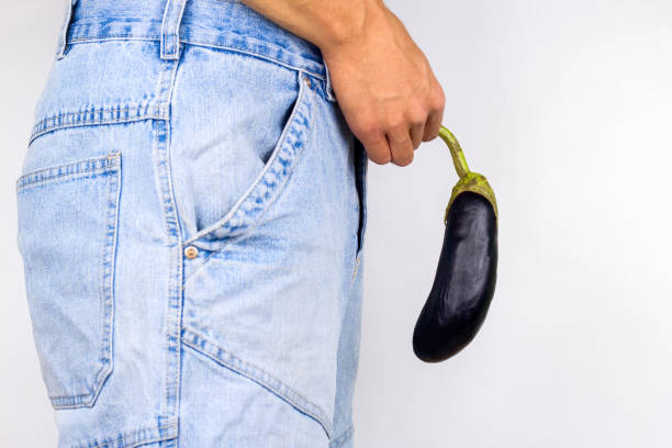 man holding eggplant near  his crotch young man holding eggplant near  his crotch erection problems stock pictures, royalty-free photos & images