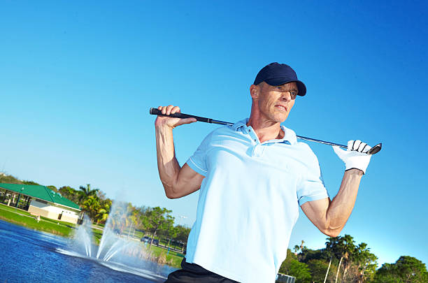 Man Holding Golf Club Against Clear Blue Sky stock photo