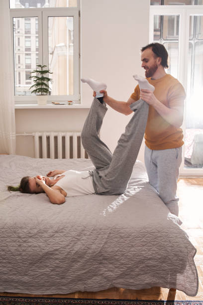 Hombre tomado de la mano de su amada mujer acostado en la cama en casa - foto de stock