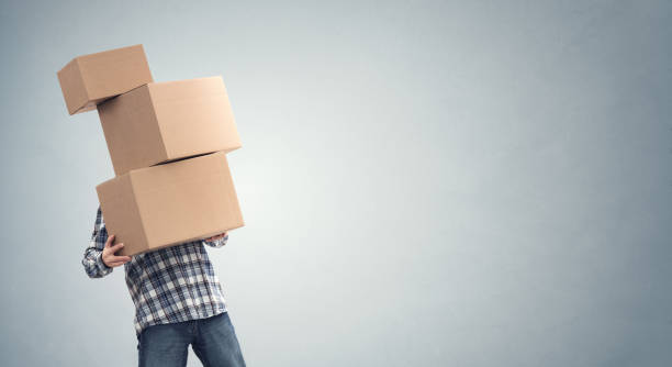 Man holding heavy cardboard boxes relocation, moving house or courier delivery Man holding heavy cardboard boxes relocation, moving house or courier delivery background relocation stock pictures, royalty-free photos & images