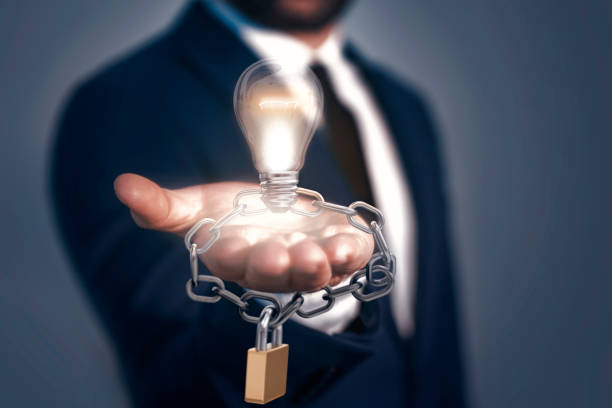 A man holding light bulb, lock and chain. Patented Idea Concept. All rights reserved  intellectual property stock pictures, royalty-free photos & images