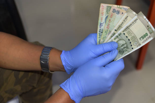 Man holding money indian rupees in hand in black medical gloves. Coronavirus crisis. Save money. Man holding money indian rupees in hand in black medical gloves. Coronavirus crisis. Save money. selective focus. INDIA CURRENCY  stock pictures, royalty-free photos & images