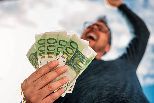 Man Holding Money Man with glasses wearing blue shirt. and holding stack of money. european union currency stock pictures, royalty-free photos & images