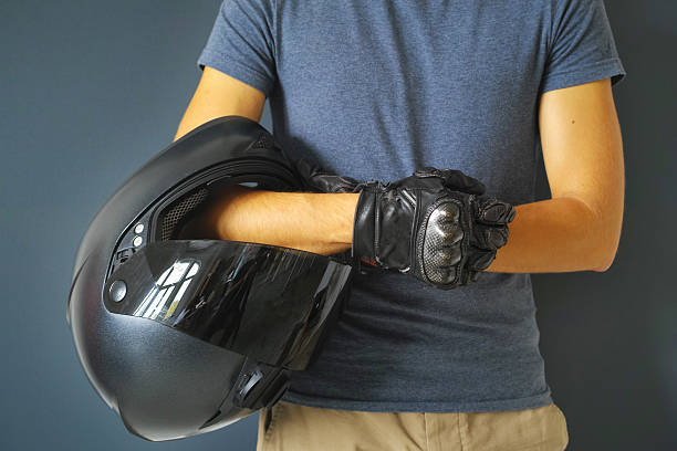 Man Holding Motorcycle Helmet On Arm With Hands In Gloves stock photo