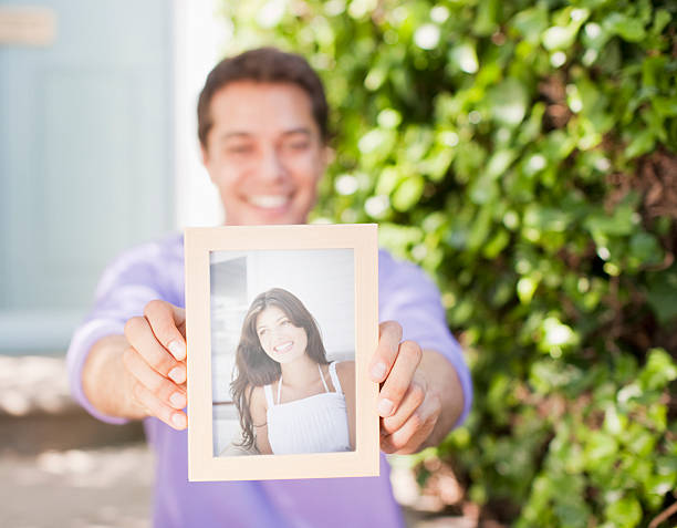 Man holding out photograph of girlfriend  holding photos stock pictures, royalty-free photos & images