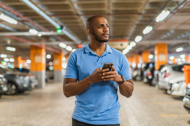 Man holding smartphone in parking lot stock photo