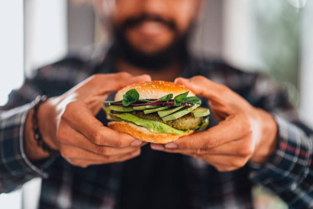 mens die veganistische kikkererwtenburger in hand houdt - veganist stockfoto's en -beelden