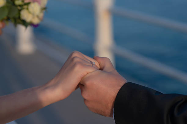 Man holding woman's hand in a romantic gesture, close-up on hands and engagement diamond ring, beautiful happy couple getting married stock photo