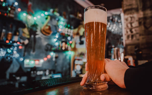 man holds a glass of beer in his hand at the bar or pub stock photo
