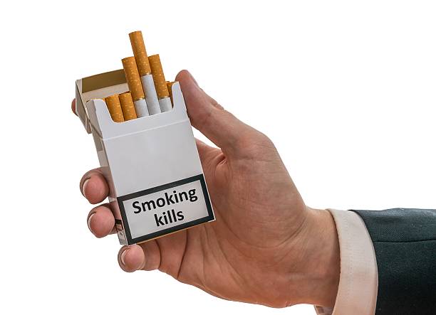 Man holds cigarette pack with warning label that smoking kills. Man holds cigarette pack in hand with warning label that smoking kills. Smoking Kills stock pictures, royalty-free photos & images