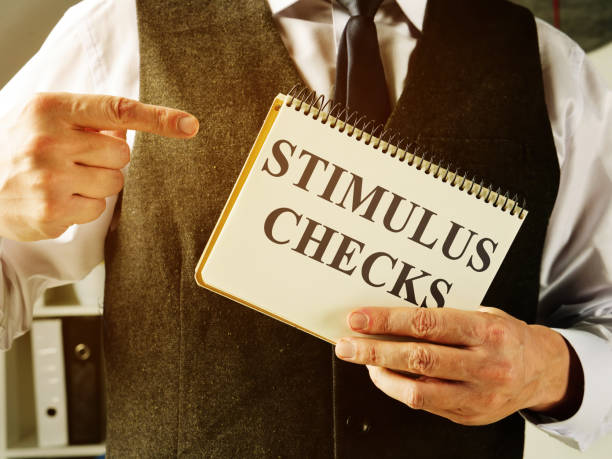Man holds information about Coronavirus stimulus checks. Man holds information about Coronavirus stimulus checks. stimulus check stock pictures, royalty-free photos & images
