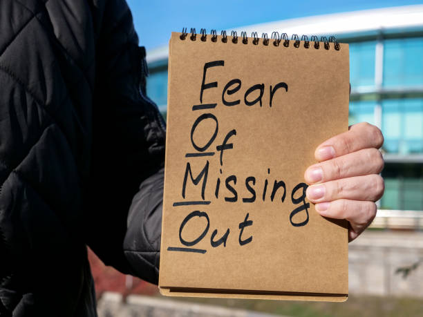 Man holds page with words FOMO fear of missing out. Man holds page with words FOMO fear of missing out. fomo stock pictures, royalty-free photos & images