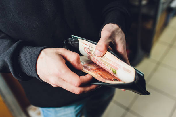 한 남자가 루블과 달러를 손에 들고, 사업가가 손에 돈을 쥐고 있다. - 러시아 루블 뉴스 사진 이미지