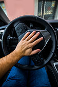 A man pushing the horn in a car's steering wheel.