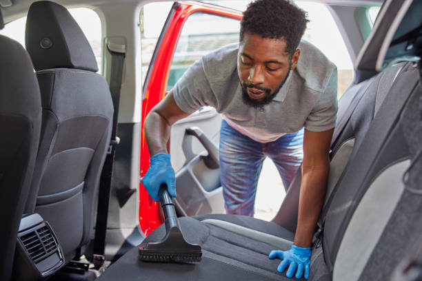 Man Hoovering  And Cleaning Rear Seats Of Car During Car Valet stock photo
