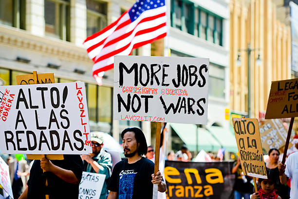 Los Angeles, USA  - May 1, 2013: Man in a crowd holding Poster  saying More jobs, not wars. During May Day Immigration reform March on Broadway, Los Angeles downtown.
