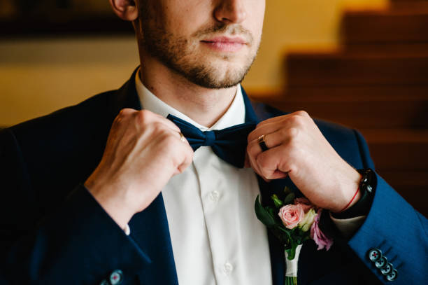 Man in a suit correcting his bow-tie. Morning preparation groom at home. Fashion photo of a man. stock photo