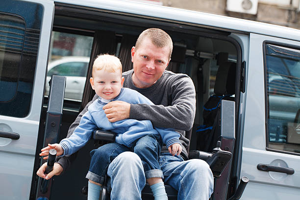 A man in a wheelchair holding a young child stock photo