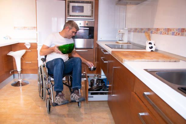 A man in a wheelchair preparing food in the kitchen stock photo