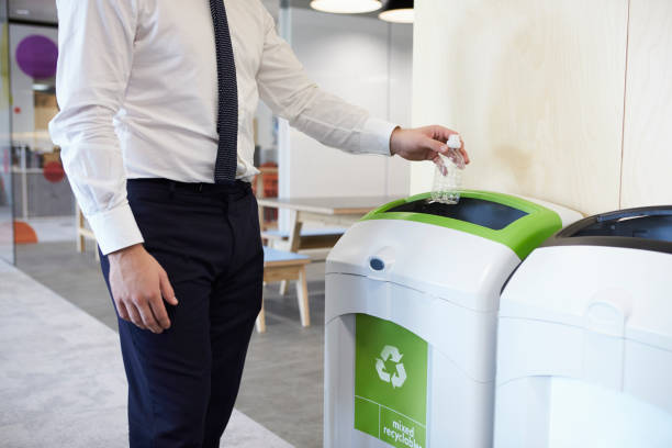 man in een kantoor gooien plastic fles in de recycling bin - recycle stockfoto's en -beelden