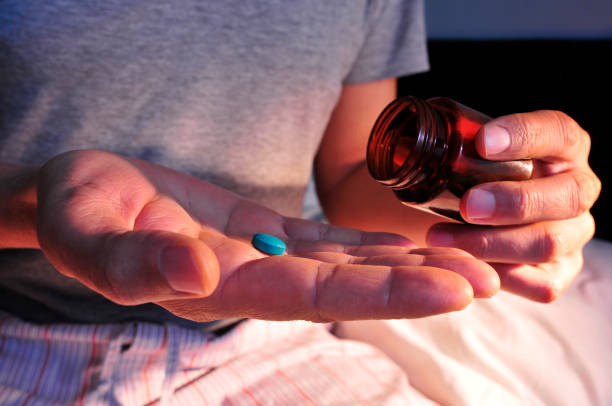 man in bed about to take a blue pill stock photo