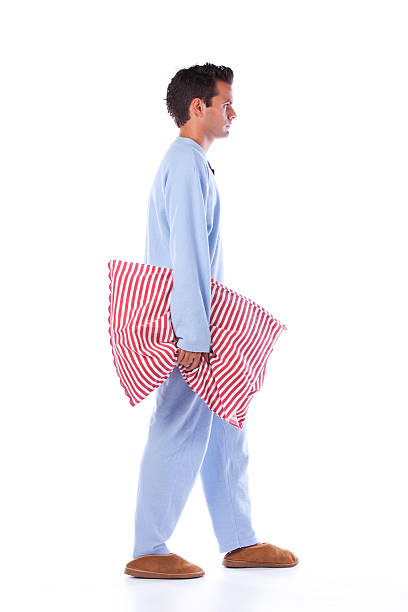 Man in blue pajamas carrying a red striped pillow stock photo