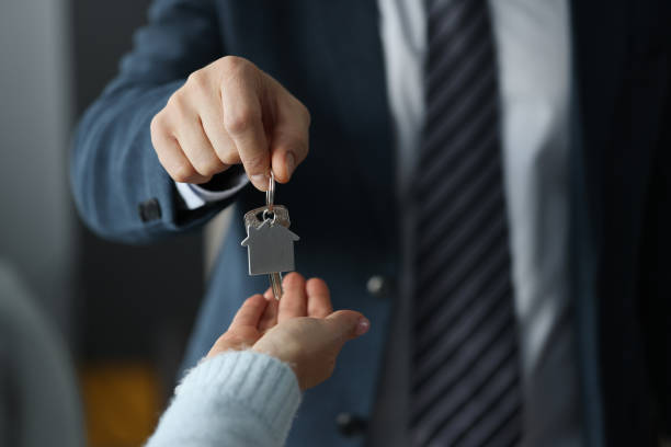 Man in business suit hands overing house keys to woman closeup stock photo