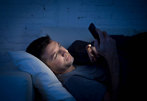 man in couch using mobile phone neetworking late night stock photo