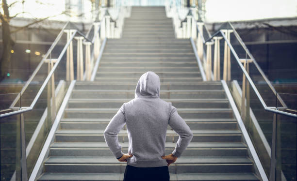 Man in hoodie preparing for stair run. Man in hoodie preparing for stair run at sunset. endurance stock pictures, royalty-free photos & images