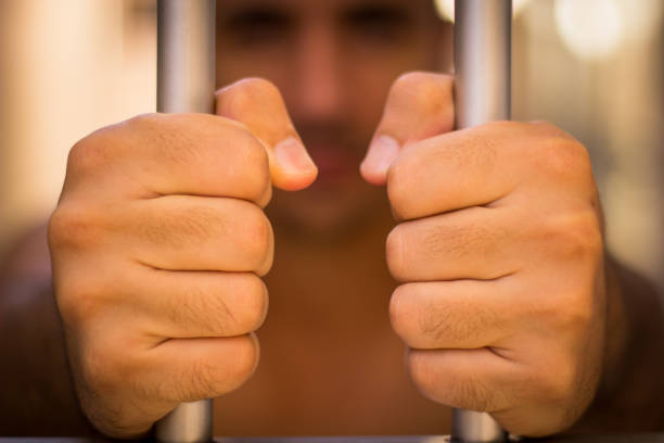 a man in jail, behind the prision bars - prision imagens e fotografias de stock
